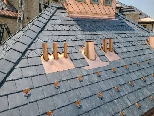 Slate roof installation with copper flashing and snow guards