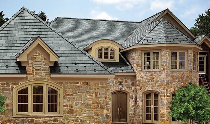Large stone home with a gray natural slate roof