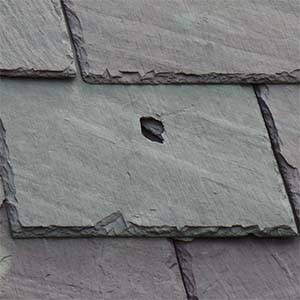 Close view of an impact hole in a natural slate roof tile