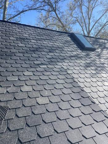 Dark synthetic slate-style roofing installed around a skylight